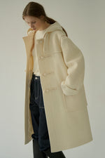 Load image into Gallery viewer, Upgrade your winter wardrobe with the Chelsea Duffle Coat. Made from premium boucle fabric, this coat features four toggle-and-cord fastening closures for a stylish touch. Stay cozy and warm with the full interior lining and functional hood. Thoughtfully placed outer pockets and an oversized fit make this coat both fashionable and functional.
