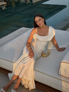 Elevate your elegance with the Celine Corset Gown, a luxurious satin masterpiece designed to flatter every figure. Featuring a corset waist that sculpts your silhouette and graceful draping at the hips, this gown enhances your natural curves. The asymmetric design highlights a delicate rosette on one shoulder and a flowing scarf on the other, adding a unique touch of sophistication. The slightly flared hemline completes this stunning look, perfect for making a memorable entrance at any special occasion.