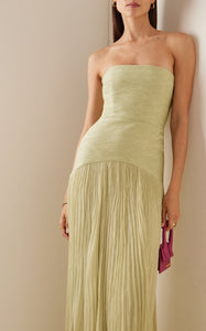 The Sunniva Plisse Strapless Gown showcases a fitted strapless bodice with a gracefully curved dropped waist, leading into a flowing plisse skirt that moves elegantly with every step. Its timeless silhouette emphasizes a refined, feminine shape, perfect for occasions that call for understated sophistication. Pair with statement earrings to elevate the look, capturing the essence of modern elegance.