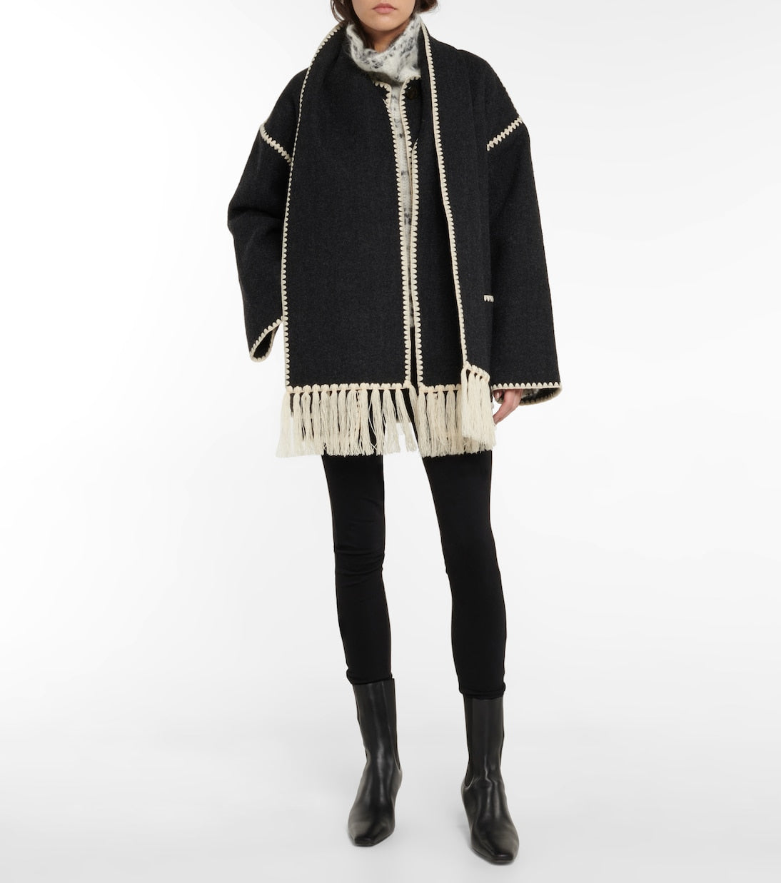 "The epitome of luxury and artistry, the Totême Veste Evelyn jacket exudes sophistication. Expertly crafted with a fringed scarf integrated into the design, this oversized wool blend jacket features dropped shoulders, wide sleeves, and contrast crochet detailing for a truly elevated look."