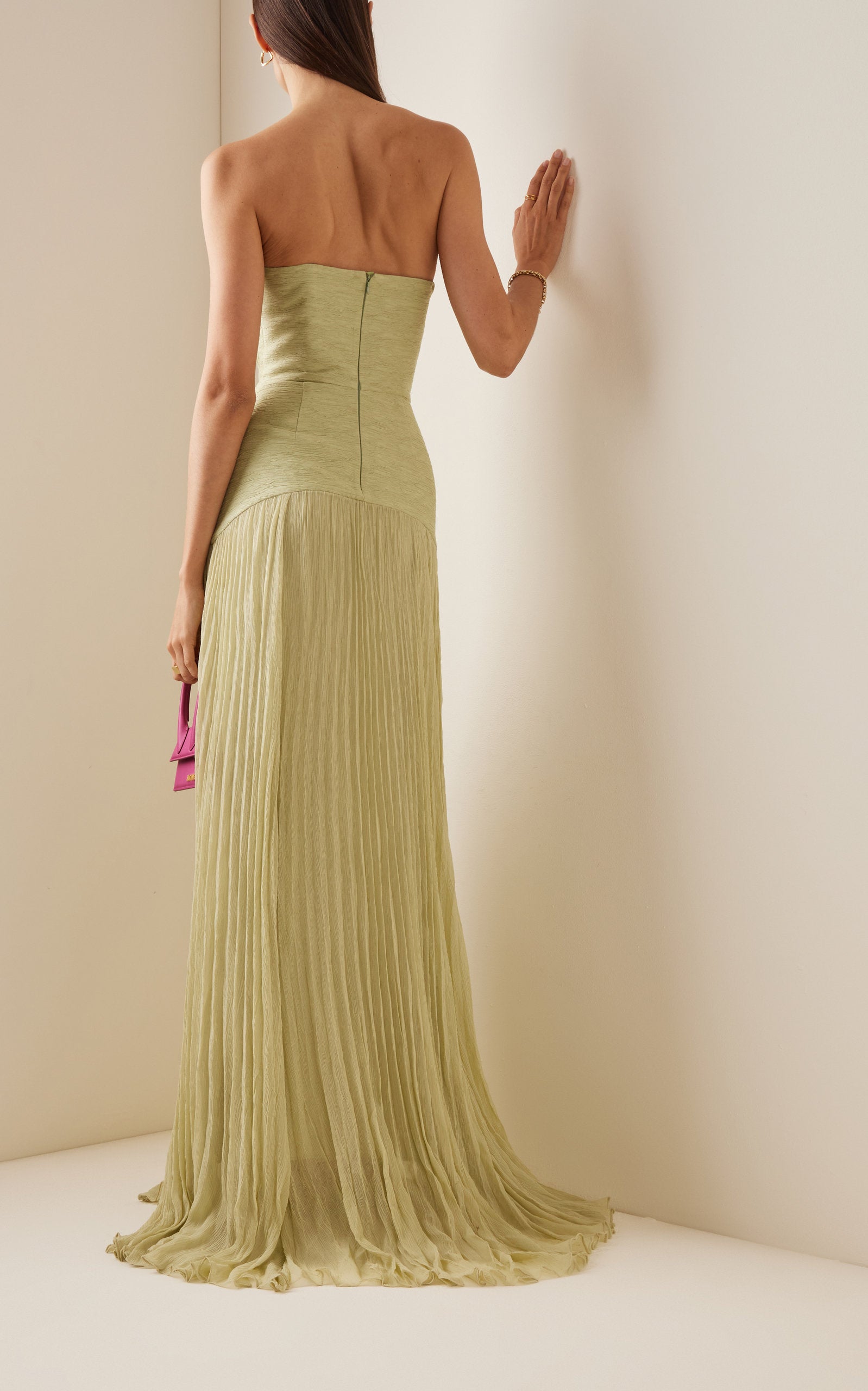 The Sunniva Plisse Strapless Gown showcases a fitted strapless bodice with a gracefully curved dropped waist, leading into a flowing plisse skirt that moves elegantly with every step. Its timeless silhouette emphasizes a refined, feminine shape, perfect for occasions that call for understated sophistication. Pair with statement earrings to elevate the look, capturing the essence of modern elegance.