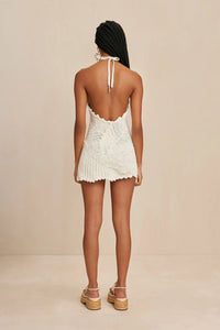 Elevate your summer style with the Undina Crochet Dress by Cult Gaia! Hand-crocheted with intricate leaf motifs, this mini-length halter dress features an open back and adjustable ties for a customizable fit. Feel confident and chic in this unique, one-of-a-kind piece.