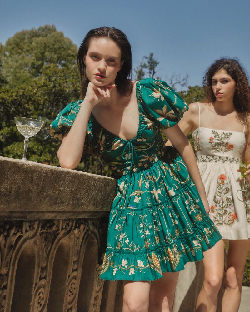 The Manzanilla Mini Dress in Neutral showcases tropical-inspired design through vibrant prints and a breezy, flattering silhouette. Made from 100% cotton poplin, it offers breathability and comfort. Key features include a deep V-neckline with an adjustable drawstring for a customized fit, short puff sleeves that add a touch of elegance, and a tiered A-line skirt that enhances movement and shape. 