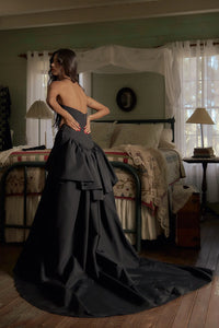 Be the life of the party in our Funny Face Gown Noir. Strapless column gown accentuates curves with built-in corset and hip padding. Side bustles and back peplum add playful flair. Functional buttons and invisible zipper down center back. Be the talk of the town in this daring and stylish gown!