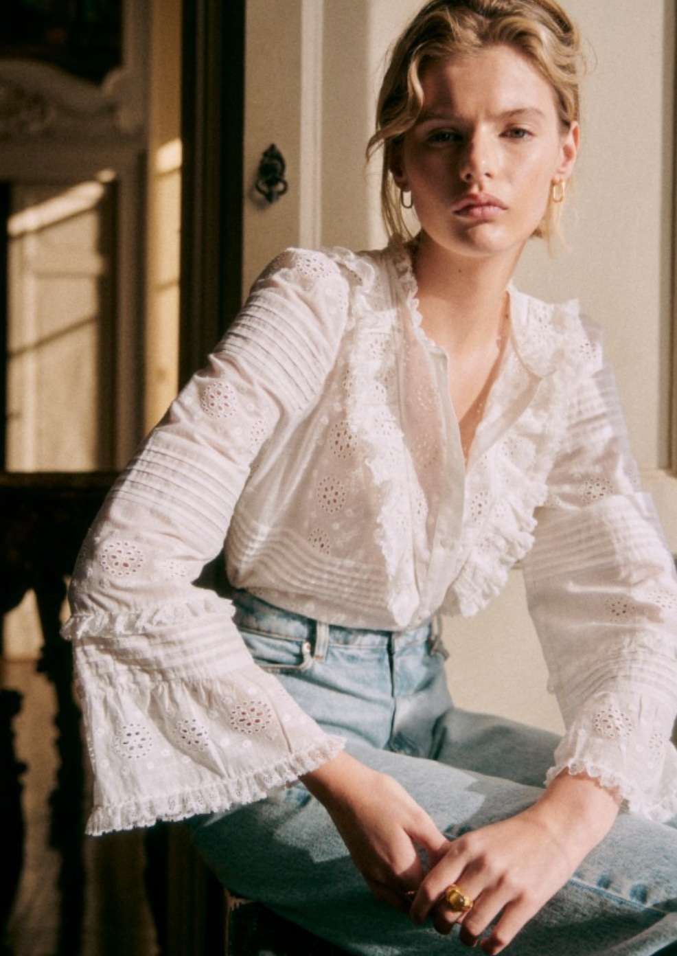 Elevate your wardrobe with the Nele Blouse. Showcasing intricate embroidered detailing and 3/4 length sleeves, this blouse exudes effortless elegance. The high ruffled collar, front ruffles, and pleat details add a touch of sophistication. Finished with delicate mother of pearl buttons, this blouse is the epitome of luxury fashion.