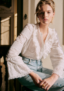 Elevate your wardrobe with the Nele Blouse. Showcasing intricate embroidered detailing and 3/4 length sleeves, this blouse exudes effortless elegance. The high ruffled collar, front ruffles, and pleat details add a touch of sophistication. Finished with delicate mother of pearl buttons, this blouse is the epitome of luxury fashion.