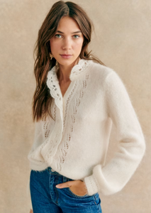 Indulge in luxury with the Cárdigan Angie. Made from a blend of wool and kid mohair, this cardigan boasts a delicately fluted silhouette and intricate crochet detailing along the button placket and neckline. The open-knit front adds a touch of artful elegance. Elevate your wardrobe with this timeless piece.