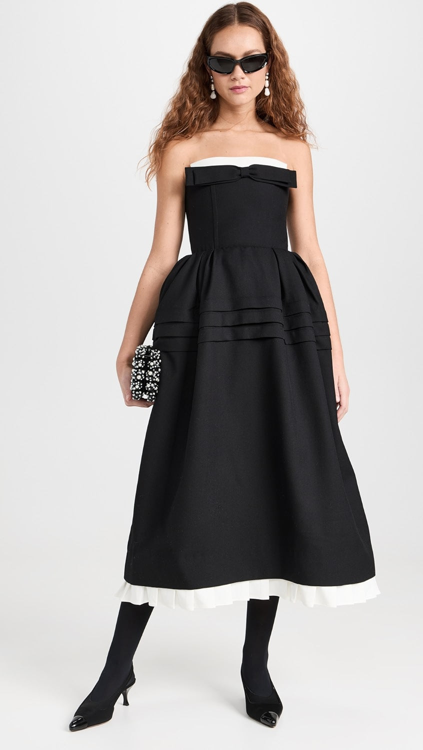 The Tuck Flower Bud Long Dress by SHUSHU/TONG features a strapless neckline with a bow accent, pleated trim at the tiered hem, and a gathering and ruffled silk organza underlay at the waist for added volume. The mid-weight, non-stretch twill fabric and boned bodice offer structure and support, while the partial lining and zip at the back provide comfort and ease. Perfect for formal events, this dress also includes on-seam hip pockets for added convenience.