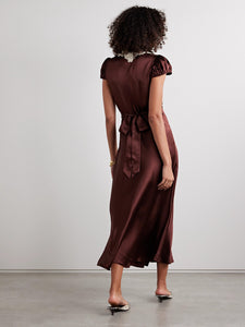 The Silk Lace-Trim Coraline Midi Dress channels the refined elegance of the 1930s with expertly crafted details. Made from lush silk satin, it gracefully drapes the body, enhanced by whimsical gathered cap sleeves. The plunging V-neckline highlights delicate embroidered scallop lace, while the fitted bodice transitions into a flattering bias-cut midi skirt. Adjustable back ties offer a personalized fit, and a subtle embroidered “D” on the bust adds a distinctive signature touch. 