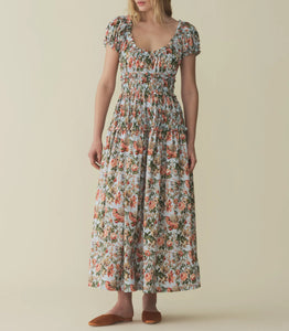 Crafted from crisp cotton and rendered in Calico Garden, a Liberty Fabrics floral from 1984 with trailing lilies, hydrangeas, roses, and dahlias, the Leanne Dress features a scoop neckline, a gathered bust, and a fitted bodice framed with petite ruffles. A third gathered panel finishes just below the hips, flaring out into an ankle-length skirt, while elastic lends give to the short puffed sleeves, bust, and waist.