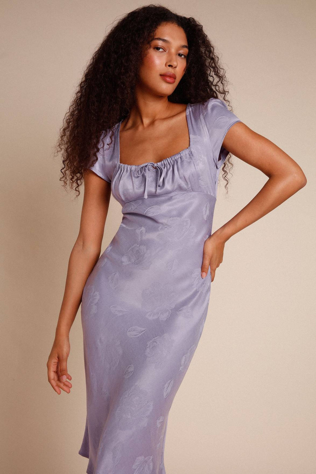 Introducing the versatile Robe Ines. This midi dress features a flattering gathered design on the chest with a unique knot detail. Its bias cut adds a touch of elegance, while the side zipper ensures a perfect fit. Available in lilac jacquard, this dress is the perfect addition to your wardrobe.