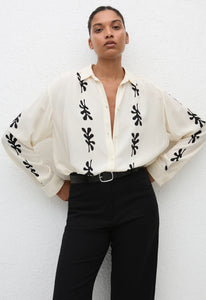 Introducing the Long Sleeve Silk Shirt, inspired by vintage styles. Made from luxurious silk crepe de chine, this oversized shirt is easy to wear without compromising style. With an exposed button placket and side splits, it's perfect for any occasion. Upgrade your wardrobe today!