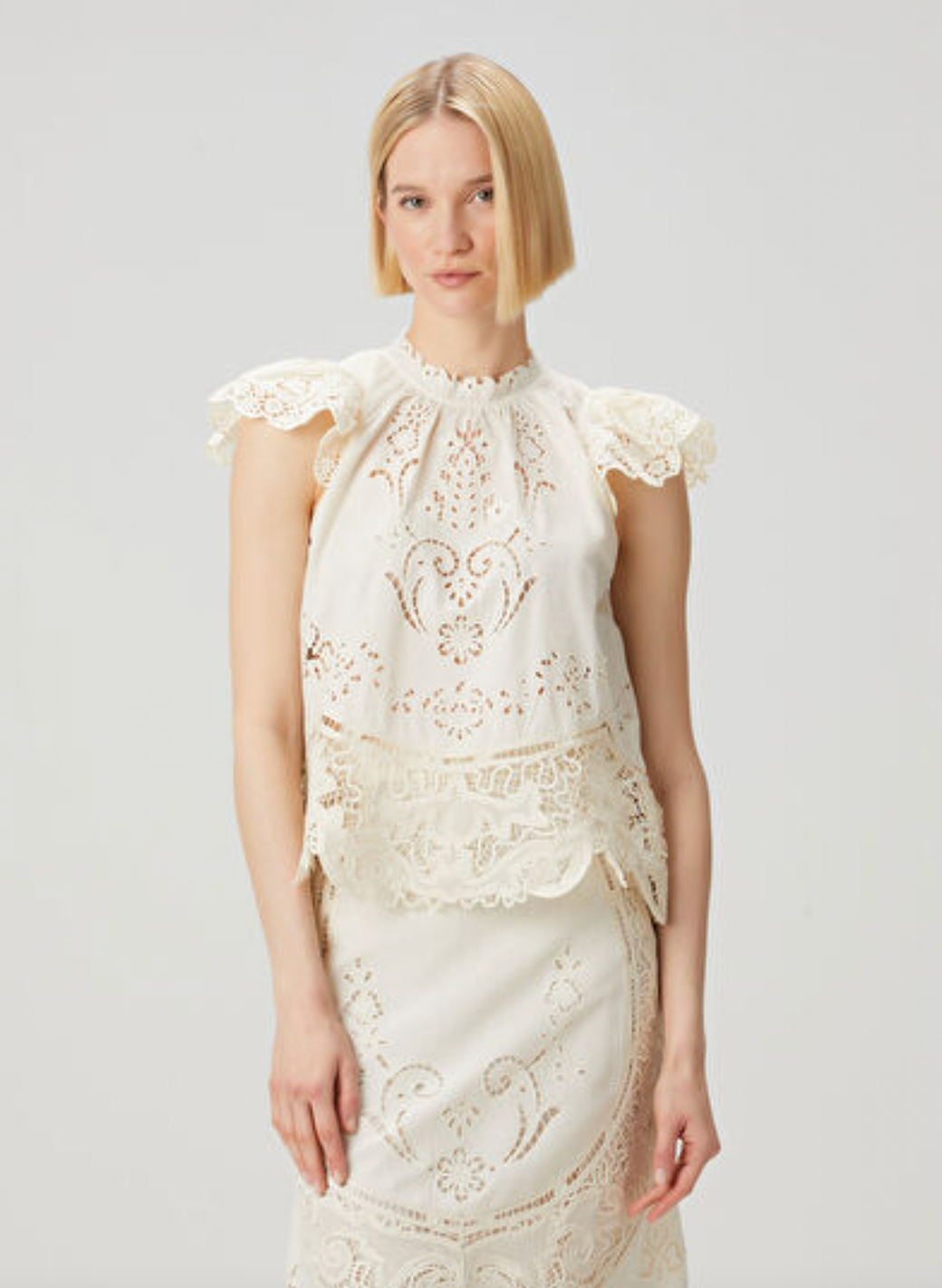 Elevate your wardrobe with the Gianna Bone Lace Blouse by SEA, featuring a refined mandarin collar that adds subtle sophistication. Delicate lace and ruffle details enhance its tank top design, blending elegance with breathable comfort. Ideal for layering or wearing alone, this blouse offers a polished look perfect for both professional settings and stylish casual occasions.