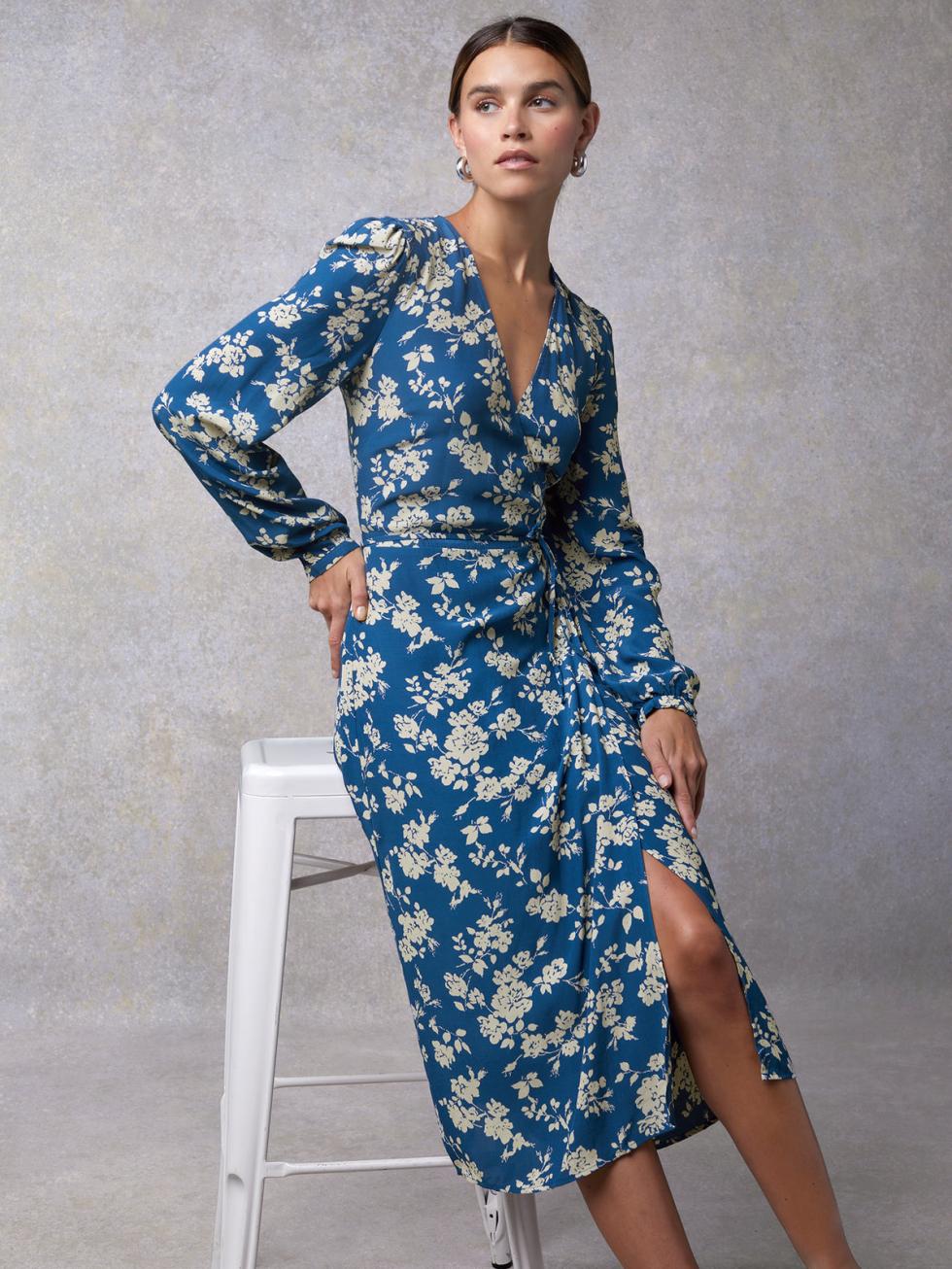 Looking for a stylish and versatile addition to your wardrobe? The Gabin Dress is the answer! This mid-length wrap dress features a beautiful two-tone blue rose floral print that is sure to turn heads. The v-neck and front fastening with buttons and a tie add a touch of elegance to this must-have dress.