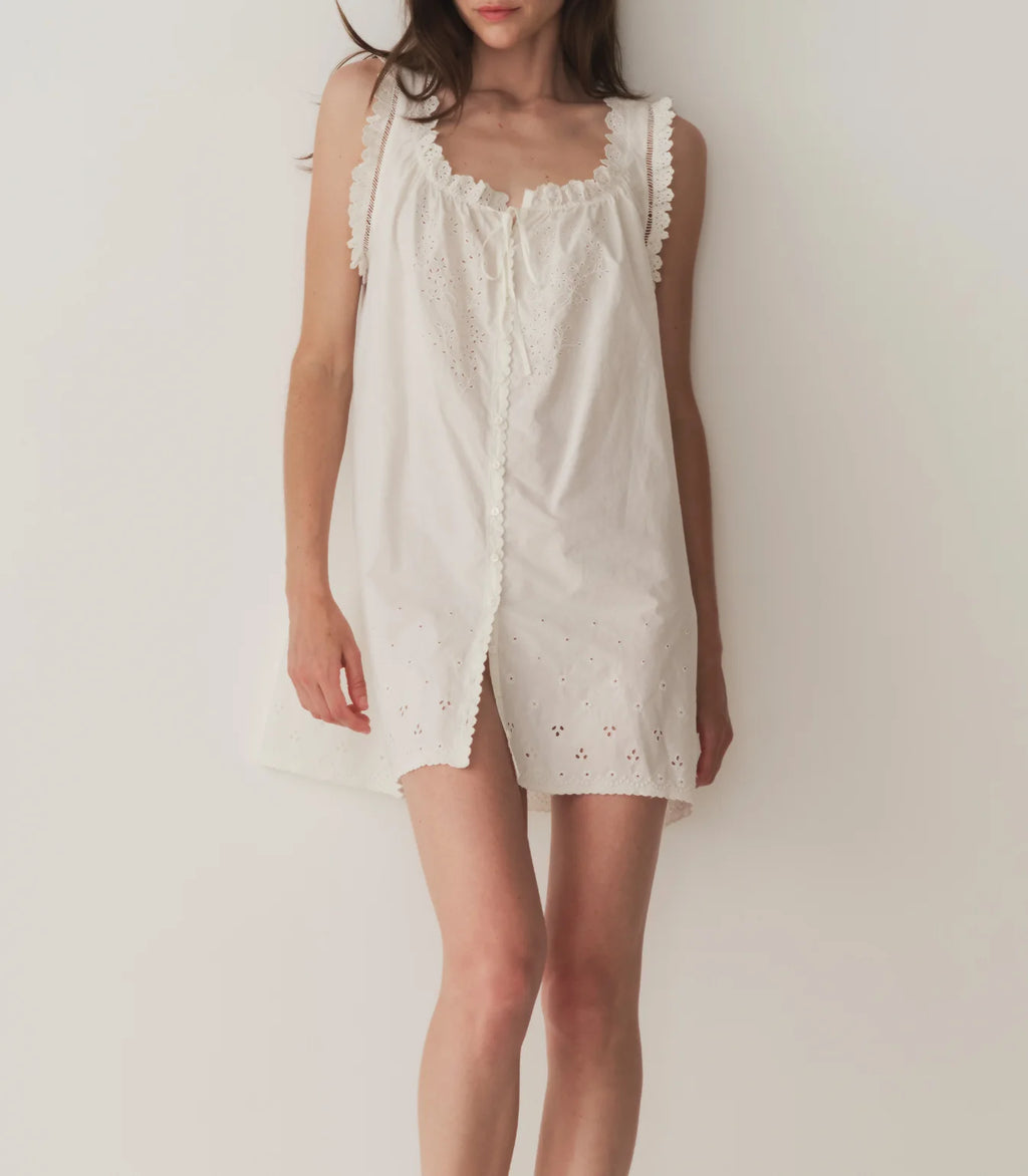 Crafted from 100% organic cotton poplin, the Nessie Dress—inspired by our bestselling Traveler Top—is a sleeveless style with a breezy cut, mother-of-pearl buttons, and a scoop neckline with a grosgrain ribbon tie. The neckline and sleeve openings are adorned with scallop eyelet detailing and ladder trim, while the yoke and mini hemline feature a floral eyelet design.