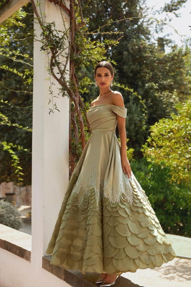 Indulge in luxury with the Aurora Gown, a soft pistachio dress made of satin fabric that exudes elegance and femininity. The open shoulders and sophisticated sleeves highlight your features while the crystal decorated hem adds a touch of brilliance. Hand-cut rose petals create a voluminous and unique look, perfect for any special occasion.