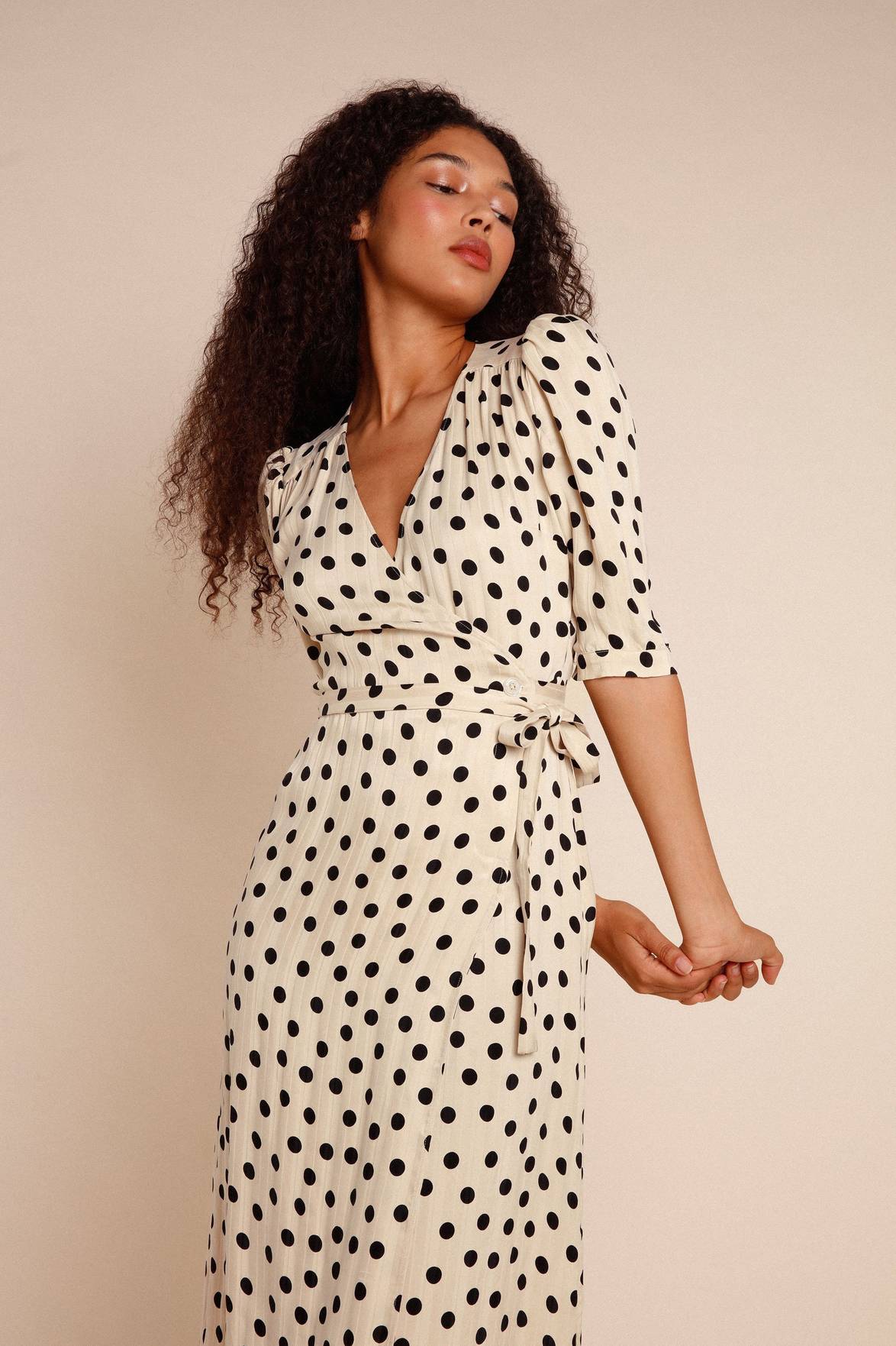 Introducing the Robe Caitlin - a stylish and versatile addition to your wardrobe. This knee-length jacquard dress features a wrap design, puffed sleeves, button accents, a waist-cinching belt, and back gathers for a flattering fit. Elevate any outfit with its playful polka dot pattern.