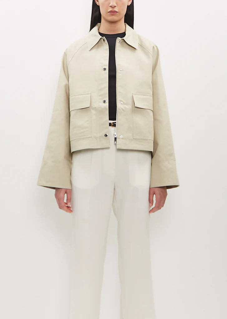 Elevate your everyday wardrobe with this sand beige cropped jacket by Toteme, crafted from sustainable organic cotton twill for a refined, eco-conscious choice. The boxy silhouette offers a contemporary silhouette that flatters effortlessly, while the spread collar and raglan sleeves deliver relaxed sophistication. Practical deep flap pockets keep essentials within reach, and the combination silver-tone zipper and press buttons closure provides versatile styling options. 