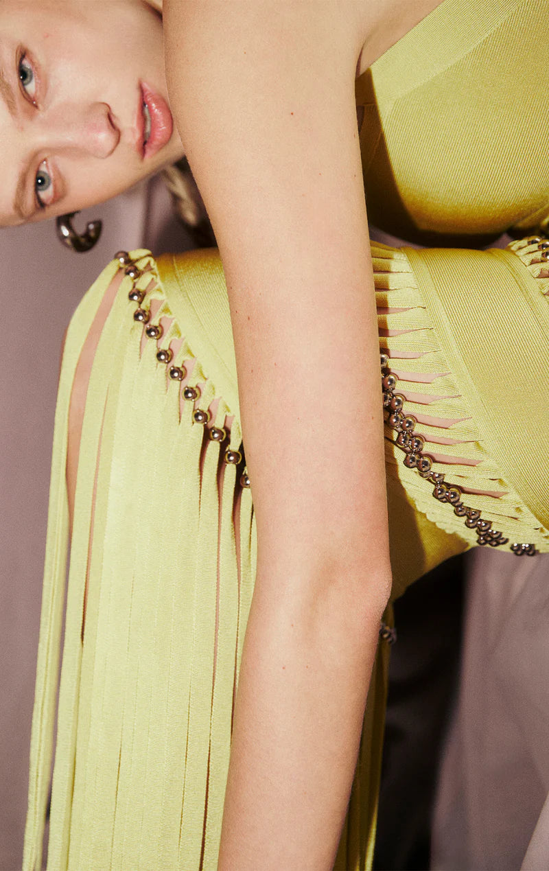 The Ines Gown by Herve Leger is a masterpiece of contemporary sophistication. Its body-contouring midi silhouette flatters every curve, while the striking square neckline commands attention. Hand-placed silver beads catch the light beautifully, creating an enchanting shimmer that draws the eye. Strategic cutouts offer tasteful glimpses of skin, adding an element of allure without compromising elegance. 