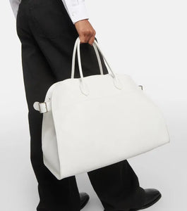 Introducing the Soft Margaux 17 Bag in White by The Row, now in luxurious grained leather. Handcrafted in Italy, this spacious tote is the perfect blend of style and comfort. Twin rolled handles, gusseted sides, and toggle closure make it both functional and fashionable. Upgrade your everyday with this must-have accessory.