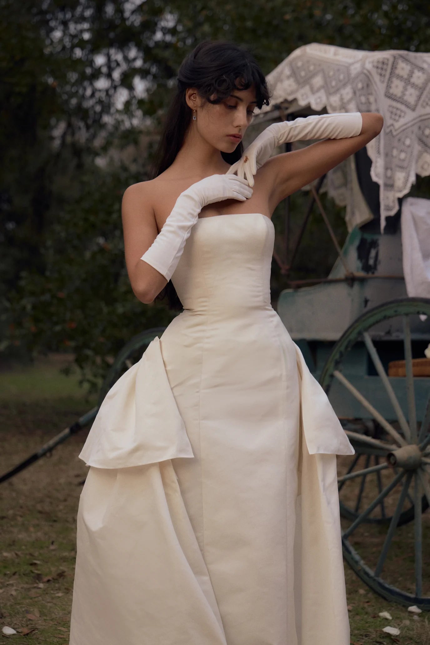 Elevate your style with our Funny Face Gown in Ivory. This strapless column gown features side bustles and a back peplum, enhanced by a built-in corset and hip padding. The fully functional buttons and invisible zipper add effortless elegance. Stand out in this unique and flattering design!