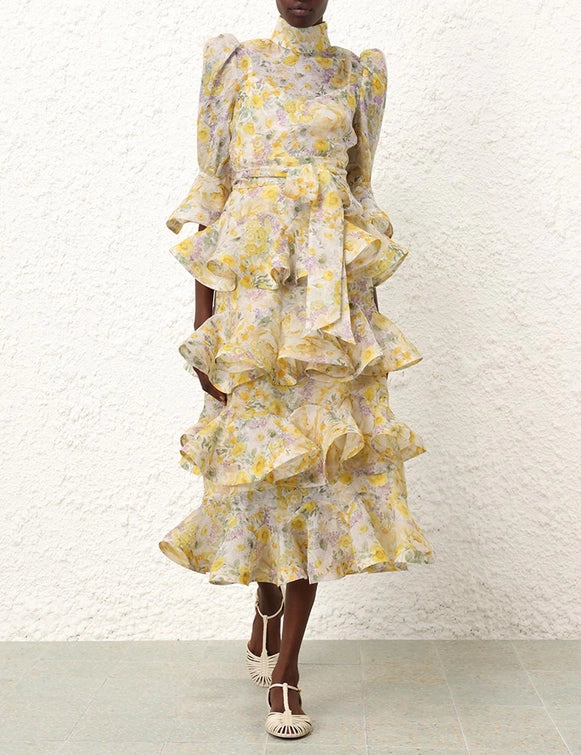 Indulge in the romantic and whimsical vibe of the Harmony Tiered Midi Dress. This silk linen organza dress boasts scalloped tiers, a stand collar, and a self tie removable belt, adorned with a vibrant citrus garden print. The fluted cuffs add a touch of elegance to this midi dress, perfect for any special occasion.