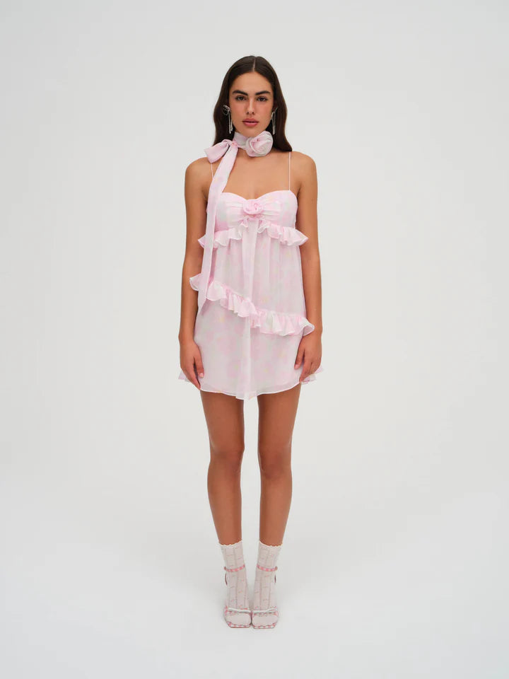 Elevate your spring wardrobe with the Ariana Mini Dress. The dainty floral print chiffon, ruched bodice, and delicate fabric rosette exudes romance. Complete the luxurious look with a matching neck scarf adorned with a rosette. Perfect for any special occasion or as a wedding guest, this dress is a must-have.