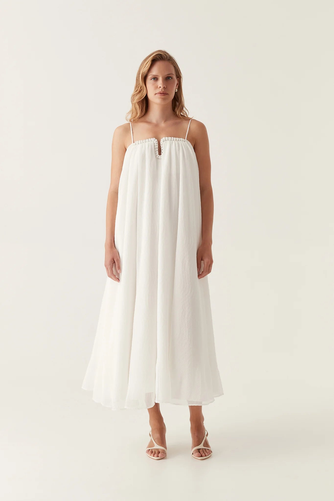 Introducing the Filigree Sweetheart Midi Dress by AJE, the epitome of elegance and luxury. Designed with a relaxed fit and adjustable straps, this dress effortlessly flatters your silhouette. The wired curve neckline and whipstitch details add a touch of sophistication, while the voluminous smock skirt and permanent plissé pleating throughout create a whimsical flow.