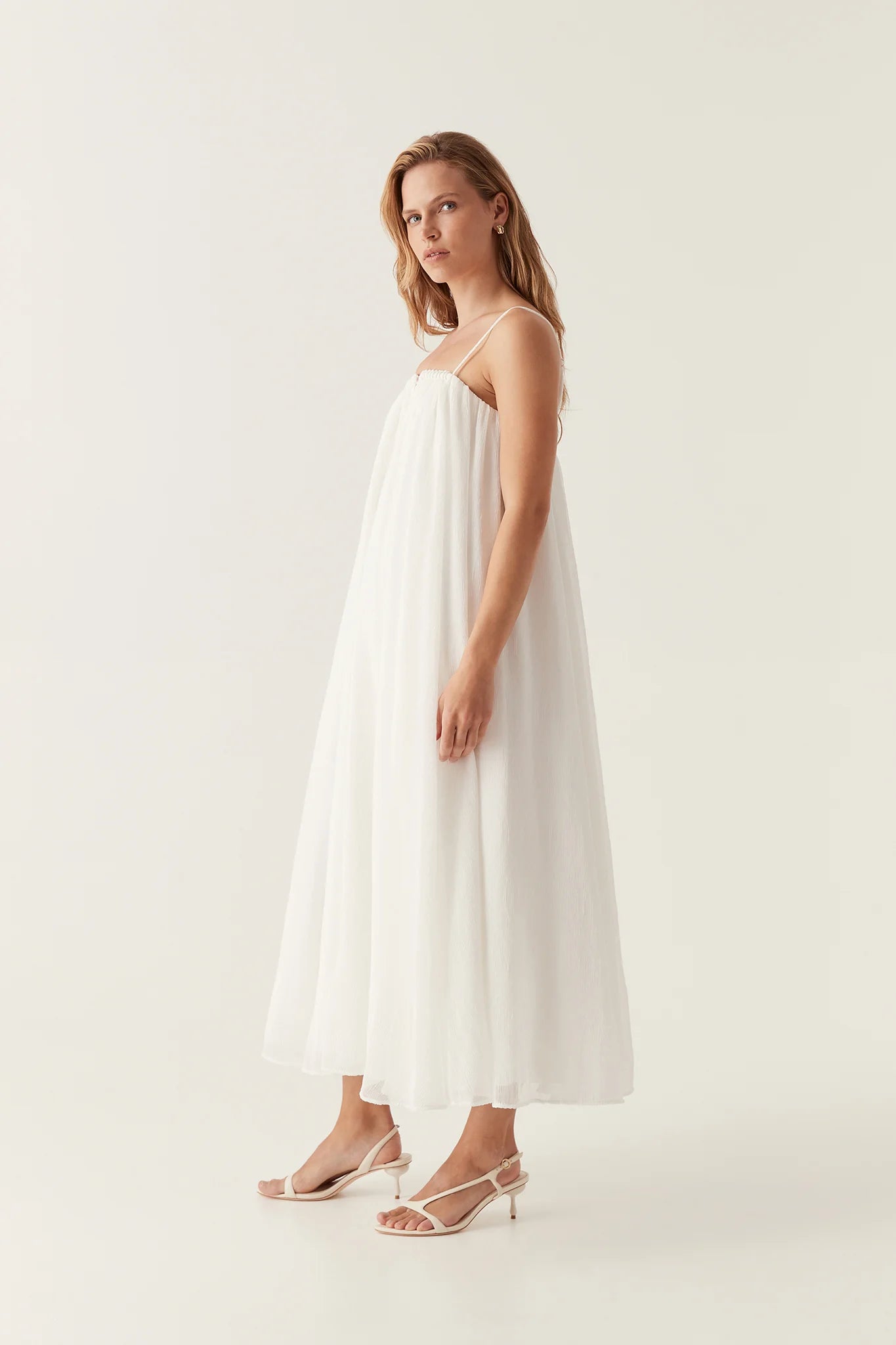 Introducing the Filigree Sweetheart Midi Dress by AJE, the epitome of elegance and luxury. Designed with a relaxed fit and adjustable straps, this dress effortlessly flatters your silhouette. The wired curve neckline and whipstitch details add a touch of sophistication, while the voluminous smock skirt and permanent plissé pleating throughout create a whimsical flow.