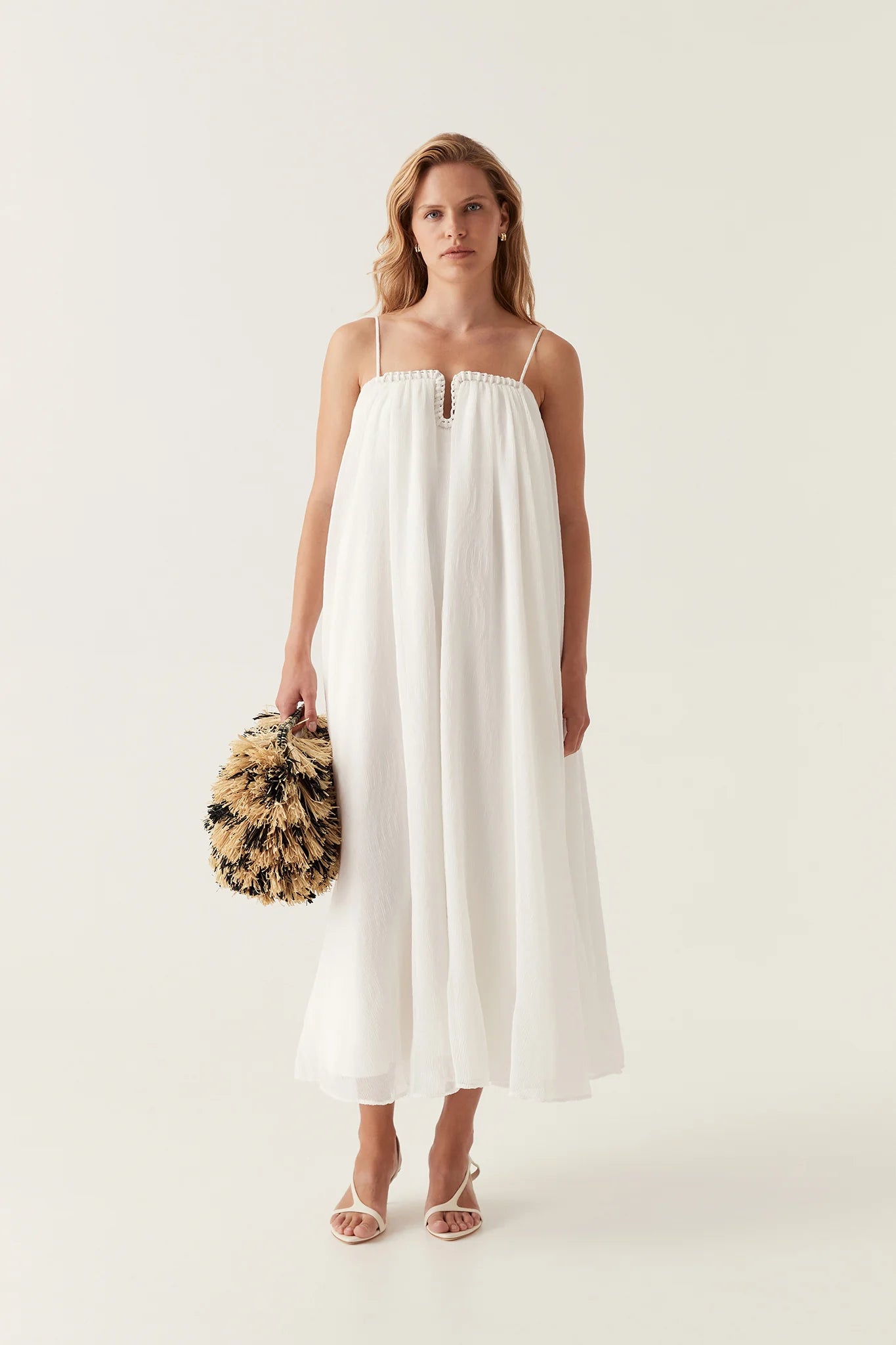Introducing the Filigree Sweetheart Midi Dress by AJE, the epitome of elegance and luxury. Designed with a relaxed fit and adjustable straps, this dress effortlessly flatters your silhouette. The wired curve neckline and whipstitch details add a touch of sophistication, while the voluminous smock skirt and permanent plissé pleating throughout create a whimsical flow.