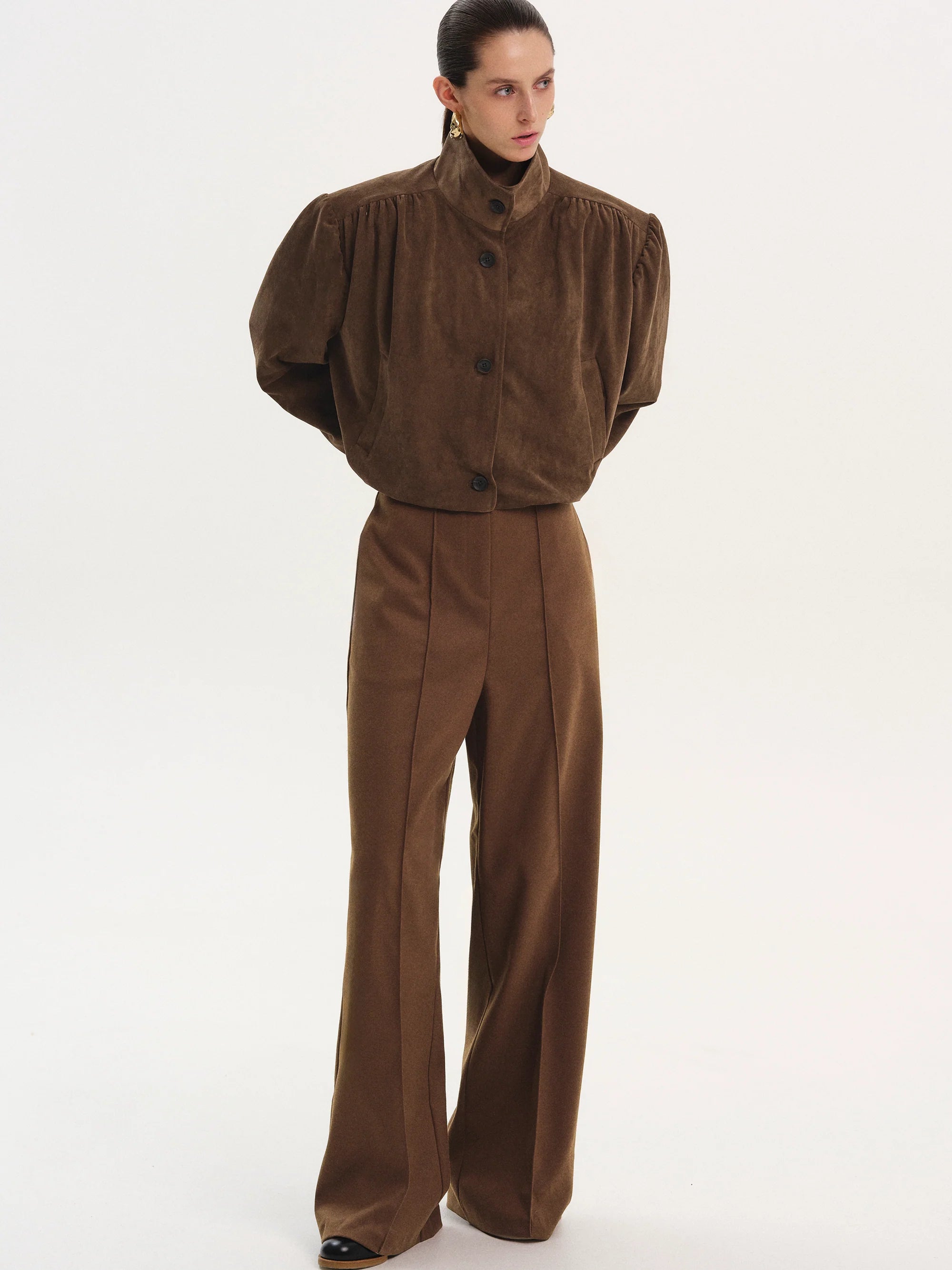 This ruched suede bomber jacket combines classic style with modern details. Its boxy shape and padded shoulders give a confident edge, while the stand collar and gathered pleats add subtle sophistication. The softly structured waistband offers a gentle blouson effect, creating a relaxed yet polished silhouette. Fully lined for comfort, this jacket is perfect for elevating any outfit with effortless charm.