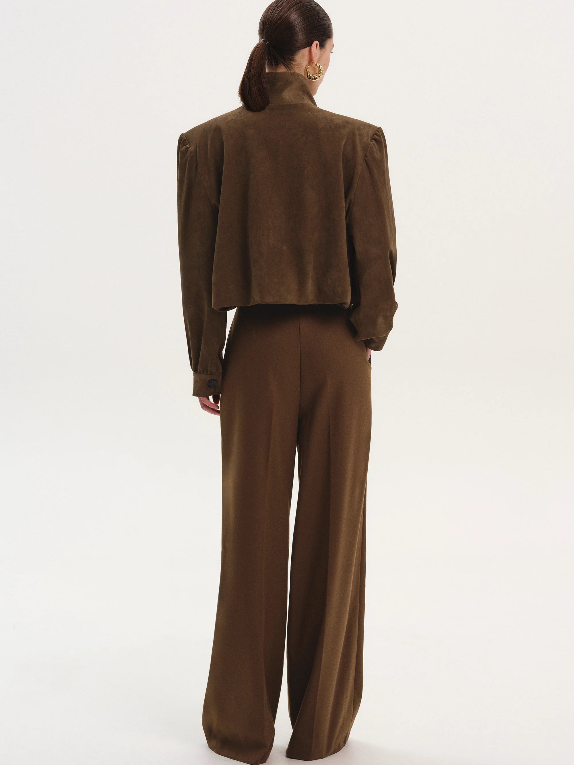 This ruched suede bomber jacket combines classic style with modern details. Its boxy shape and padded shoulders give a confident edge, while the stand collar and gathered pleats add subtle sophistication. The softly structured waistband offers a gentle blouson effect, creating a relaxed yet polished silhouette. Fully lined for comfort, this jacket is perfect for elevating any outfit with effortless charm.