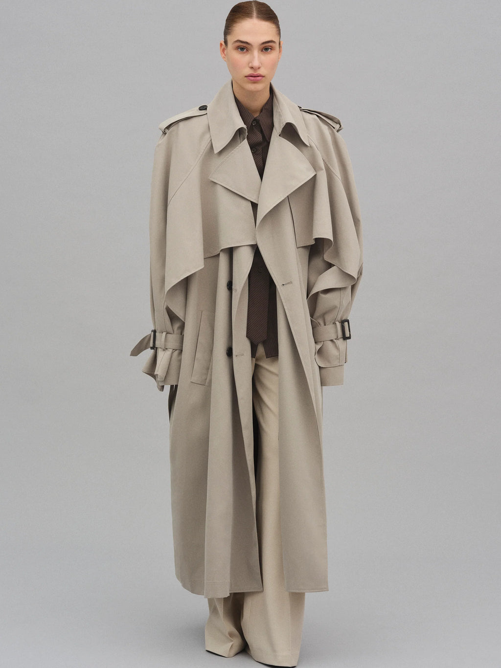 This Caped Trench Coat elevates the traditional silhouette with voluminous cape-like accents draped from the shoulders and sleeves, blending architectural boldness with classic refinement. Fully lined for a polished finish, it offers both visual impact and lasting comfort, making it a sophisticated addition to any wardrobe.