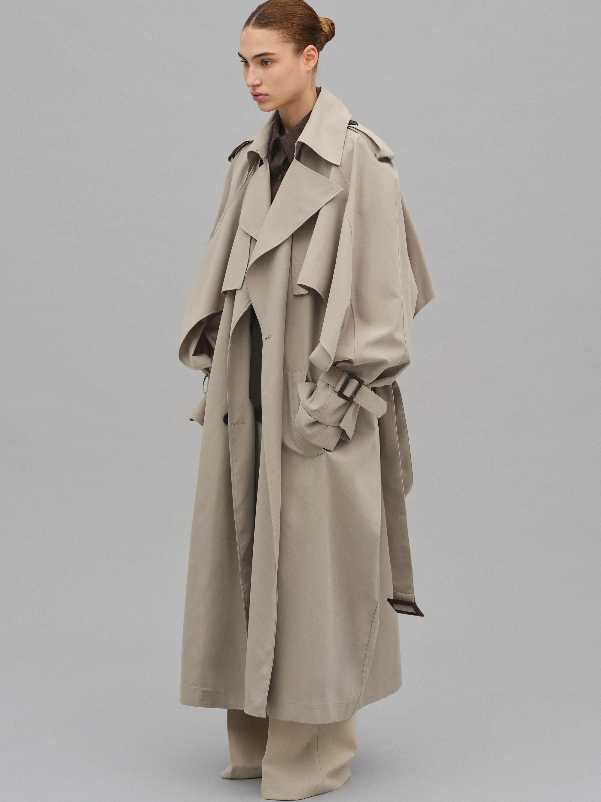 This Caped Trench Coat elevates the traditional silhouette with voluminous cape-like accents draped from the shoulders and sleeves, blending architectural boldness with classic refinement. Fully lined for a polished finish, it offers both visual impact and lasting comfort, making it a sophisticated addition to any wardrobe.