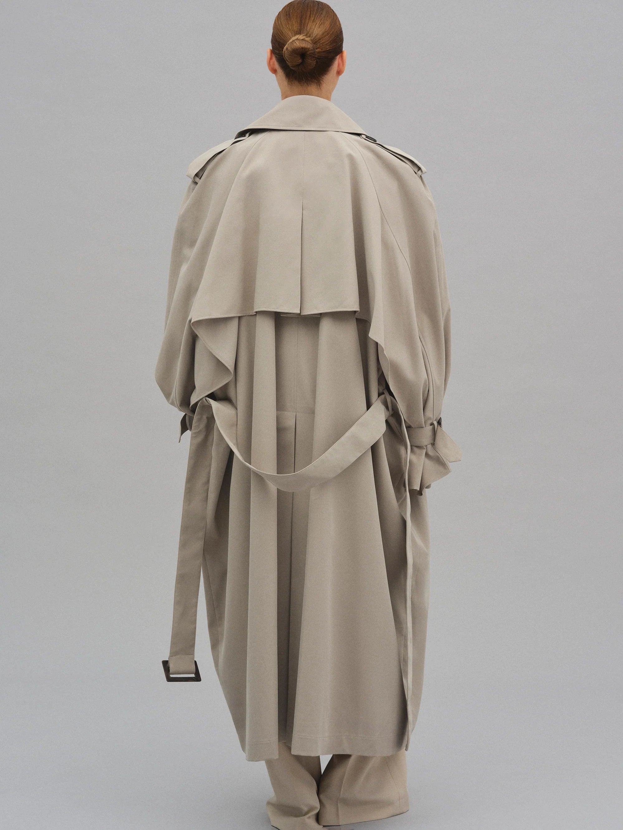This Caped Trench Coat elevates the traditional silhouette with voluminous cape-like accents draped from the shoulders and sleeves, blending architectural boldness with classic refinement. Fully lined for a polished finish, it offers both visual impact and lasting comfort, making it a sophisticated addition to any wardrobe.