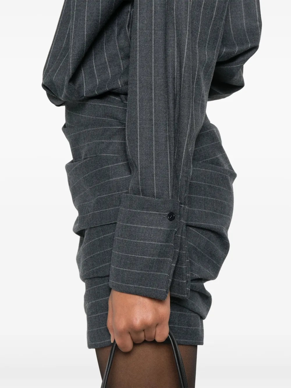 The Narine mini dress by Retrofete features a sophisticated charcoal and light grey pinstripe pattern, crafted with expert tailoring. It includes a concealed front button fastening and side zip for a seamless look, while shoulder pads and ruched detailing add structured elegance. The dress is finished with a pointed flat collar, long sleeves with buttoned cuffs, a straight hem, and full lining for comfort and quality. Ideal for those seeking a refined, modern silhouette with subtle detailing.