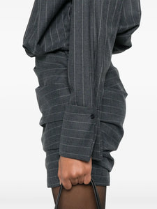 The Narine mini dress by Retrofete features a sophisticated charcoal and light grey pinstripe pattern, crafted with expert tailoring. It includes a concealed front button fastening and side zip for a seamless look, while shoulder pads and ruched detailing add structured elegance. The dress is finished with a pointed flat collar, long sleeves with buttoned cuffs, a straight hem, and full lining for comfort and quality. Ideal for those seeking a refined, modern silhouette with subtle detailing.