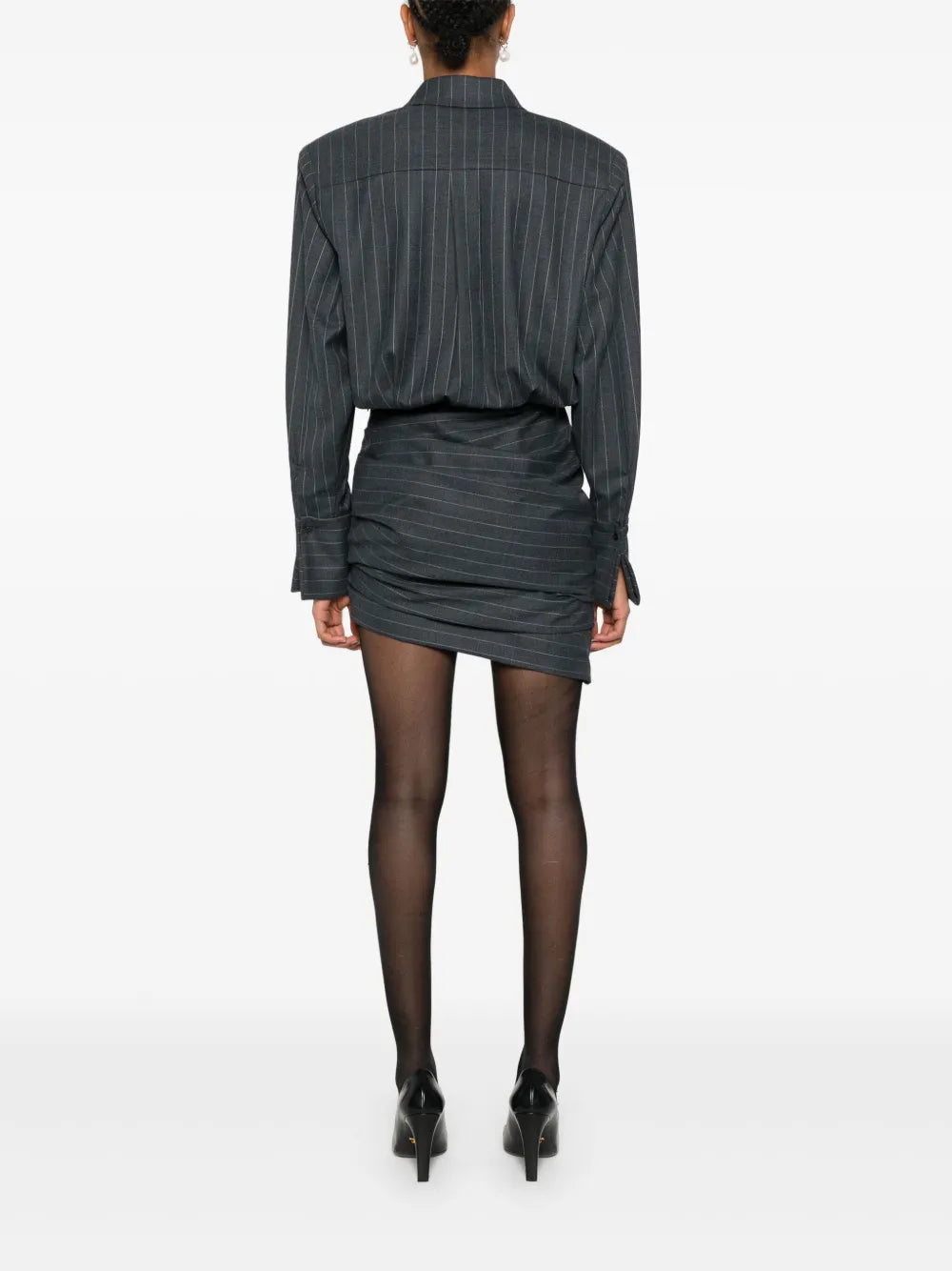 The Narine mini dress by Retrofete features a sophisticated charcoal and light grey pinstripe pattern, crafted with expert tailoring. It includes a concealed front button fastening and side zip for a seamless look, while shoulder pads and ruched detailing add structured elegance. The dress is finished with a pointed flat collar, long sleeves with buttoned cuffs, a straight hem, and full lining for comfort and quality. Ideal for those seeking a refined, modern silhouette with subtle detailing.