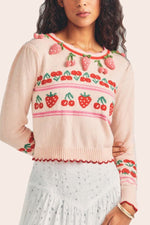 Load image into Gallery viewer, The Renton Pullover is a charming blend of cotton and wool, adorned with a delightful strawberry and cherry motif. Hand-crocheted strawberries add a touch of whimsy. With a shrunken fit and ribbed neckline, cuffs, and border, this sweater is both cozy and stylish. Adorned with strawberry buttons down the back, it&#39;s the perfect addition to any wardrobe.
