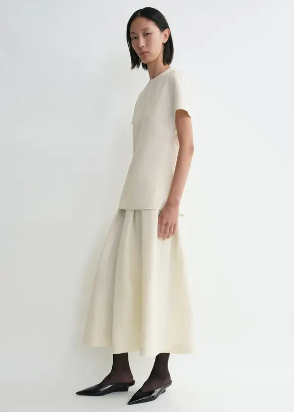 Elevate your wardrobe with this sophisticated TOTEME cap-sleeve top, designed for the modern woman who values refined elegance. The longline silhouette flatters your frame while the distinctive twisted seams add architectural interest to every wear. Crafted from luxurious double-faced cady blended with wool and silk, this piece offers both comfort and durability. The concealed back zipper ensures a seamless, polished look. 