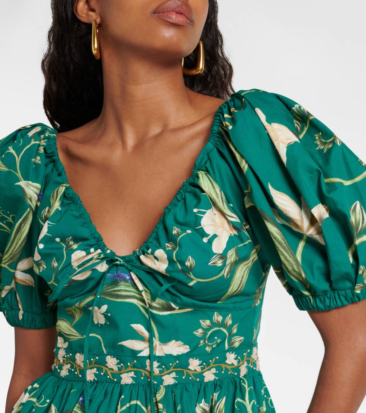 The Manzanilla Mini Dress in Neutral showcases tropical-inspired design through vibrant prints and a breezy, flattering silhouette. Made from 100% cotton poplin, it offers breathability and comfort. Key features include a deep V-neckline with an adjustable drawstring for a customized fit, short puff sleeves that add a touch of elegance, and a tiered A-line skirt that enhances movement and shape. 