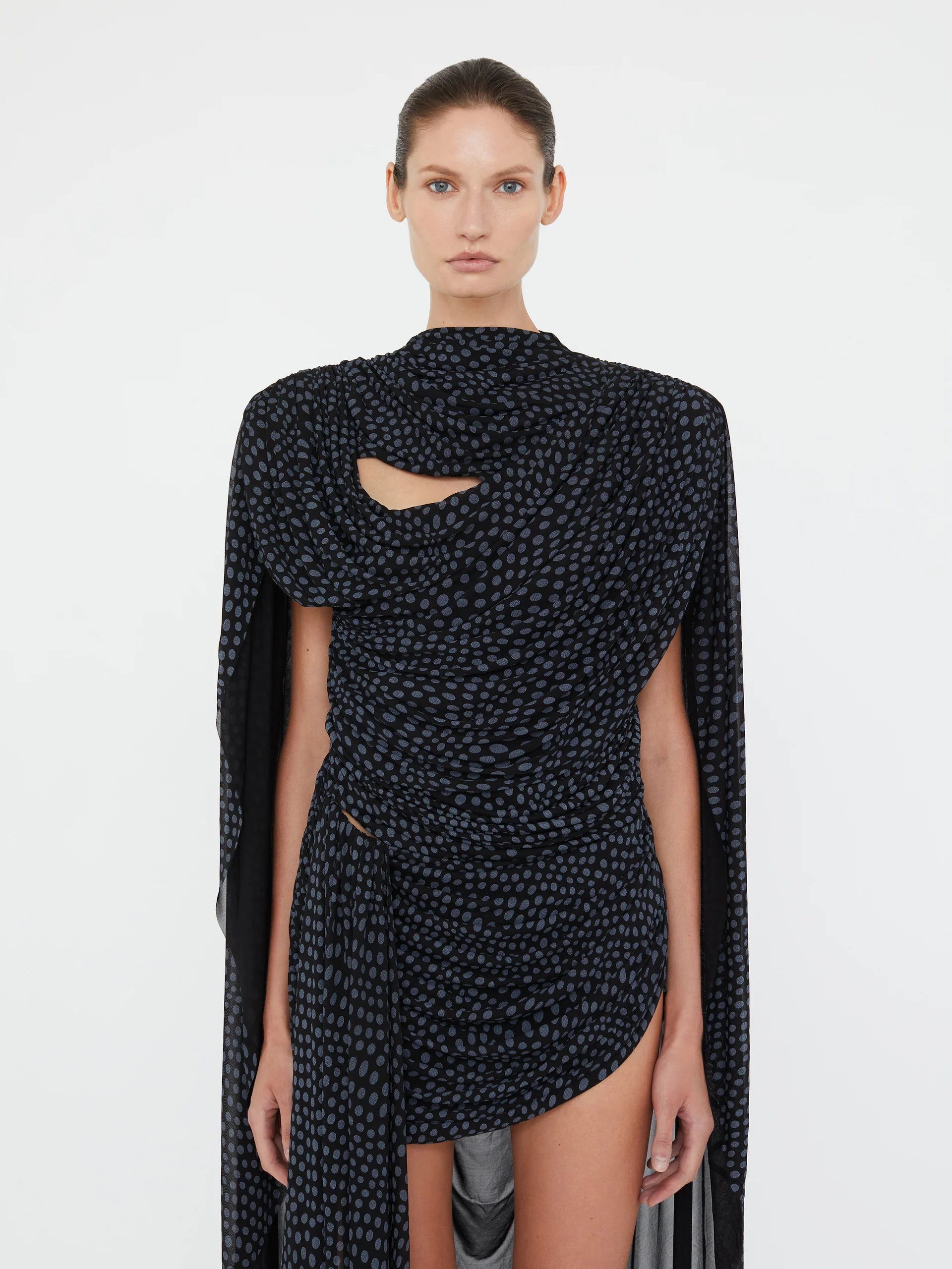 Embrace a nostalgic 90s vibe with the Torrent Draped Mini Dress by Christopher Esber, featuring a striking blue on black warped polka dot pattern inspired by a summer rain shower. The mini silhouette, enriched with gathered and cinched drapes, creates dynamic movement and captivating dimension. Its asymmetric draped skirt and fully lined construction offer effortless style and comfort, making it the perfect choice for standing out with subtle, artistic flair. 