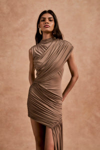 The Ravenna Mini Dress in Taupe offers a graceful silhouette with its asymmetrical high-low hemline and ruched detailing. Designed to fit true to size, this sleeveless, form-fitting dress effortlessly enhances your natural shape, making it ideal for special events. Its elegant taupe color pairs beautifully with gold or silver jewelry and classic pumps, ensuring a polished and confident look every time.
