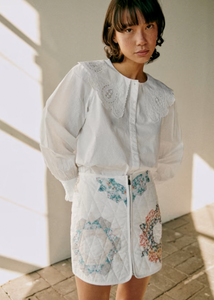 The Flavie Shirt by Sezane combines timeless elegance with a standout design featuring a large embroidered collar that adds a touch of sophistication to your look. Its long sleeves and buttoned front offer both comfort and versatility, making it perfect for dressing up or down. Elevate your wardrobe with this statement piece that effortlessly blends classic style and unique detail.