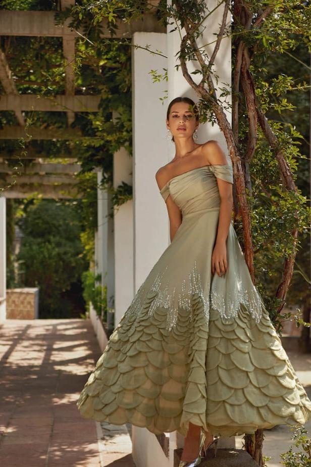 Indulge in luxury with the Aurora Gown, a soft pistachio dress made of satin fabric that exudes elegance and femininity. The open shoulders and sophisticated sleeves highlight your features while the crystal decorated hem adds a touch of brilliance. Hand-cut rose petals create a voluminous and unique look, perfect for any special occasion.