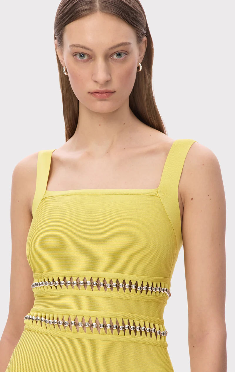 The Ines Gown by Herve Leger is a masterpiece of contemporary sophistication. Its body-contouring midi silhouette flatters every curve, while the striking square neckline commands attention. Hand-placed silver beads catch the light beautifully, creating an enchanting shimmer that draws the eye. Strategic cutouts offer tasteful glimpses of skin, adding an element of allure without compromising elegance. 