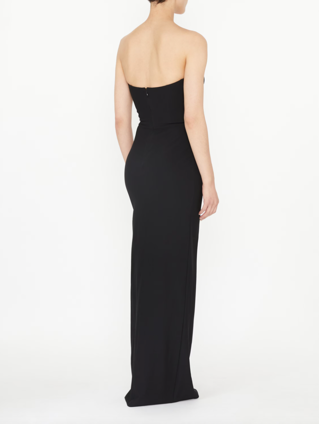 This black strapless evening dress by NENSI DOJAKA features a fitted silhouette that accentuates your figure with elegance. Crafted from high-quality Italian material, it showcases a distinctive keyhole neckline and a high slit, adding a refined and striking edge. The zip fastening at the back ensures a secure and tailored fit, making it an exceptional choice for sophisticated occasions.