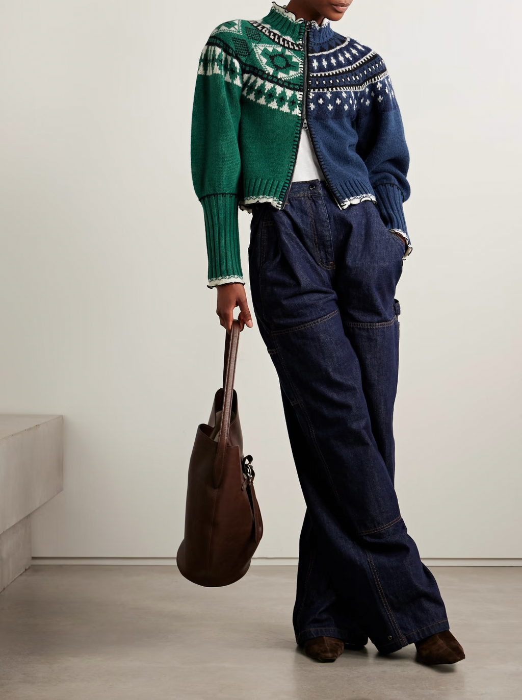 Sea's Linea cardigan masterfully blends two distinct aesthetics into one captivating piece. Crafted from sumptuous merino wool, this intarsia-knit design features Fair Isle-inspired motifs that create visual intrigue, while delicate ruffled trims add an unexpected feminine touch. The clever split construction gives the illusion of contrasting styles sewn together, making it a conversation-starting layer that transforms any basic turtleneck into an effortlessly sophisticated ensemble. 