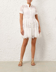 This cotton mini dress features short sleeves and a front center placket for a polished look. Its delicate scalloped hemline and intricate placement trim add refined detailing, while the included separate slip ensures comfortable coverage and smooth layering. Ideal for warm weather, this dress combines breathable fabric with elegant design elements.