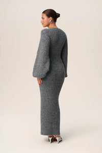 Indulge in luxury with the Luzern Knit Dress. This maxi dress in grey melange is expertly crafted from a soft and cozy wool-blended fabric, ensuring both style and warmth. It features a flattering hourglass fit, front button-up closure, and elegant V-neck collar. Complete the look with full-length balloon sleeves and distinctive cuffs for a truly sophisticated and exclusive feel.